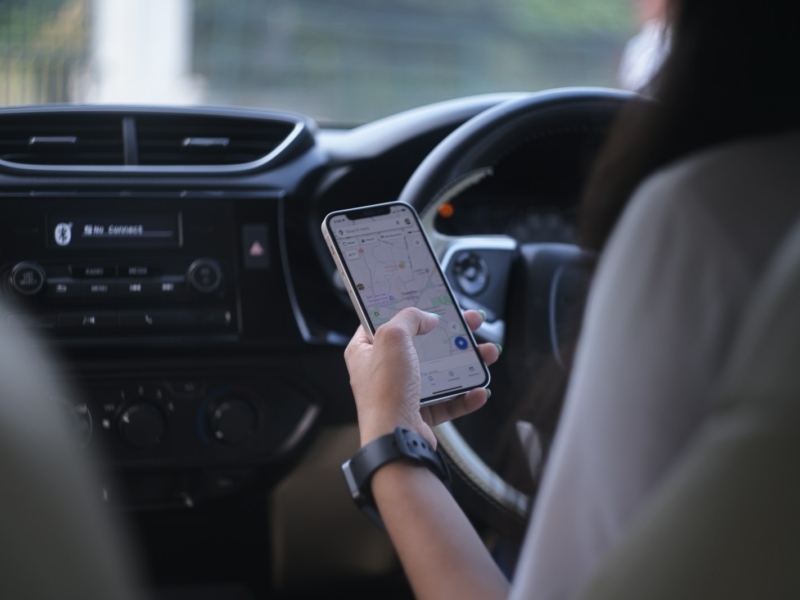 A woman holding a cell phone while driving a car
